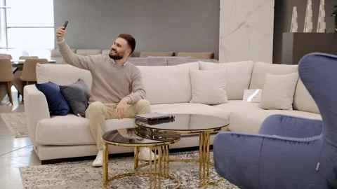 Man taking selfie sitting on couch in furniture store Stock Footage 322550171