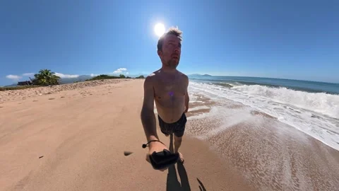 Man Taking a Selfie While Walking Along a Secluded Beach Stock Footage 345261784