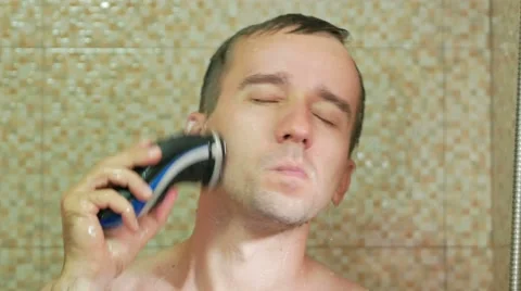 A man taking a shower and shave with an electric razor. Waterproof rotary razor Stock Footage 67521264