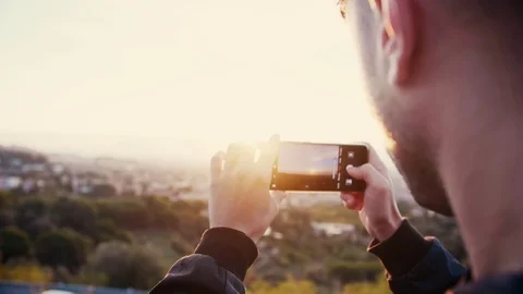 Man taking smartphone picture of sunset or sunrise cityscape from top of city Stock Footage 102685251