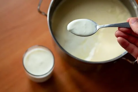 Man taking some yogurt from pan to cup for a meal Stock Photos
