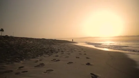 Man is taking a stroll along the beach as the sun sets Stock Footage 293157982