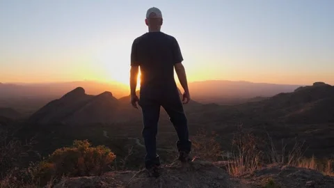 A man taking-in the sunset from a mountain summit Stock Footage 335422073