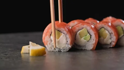 Man taking sushi using sticks. Philadelphia sushi from salmon, rice, avocado. Stock Footage 152065926