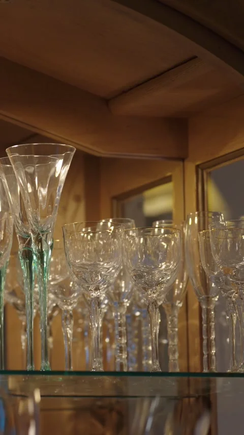 Man taking two wine glasses out of china hutch vertical video Stock Footage 284900352