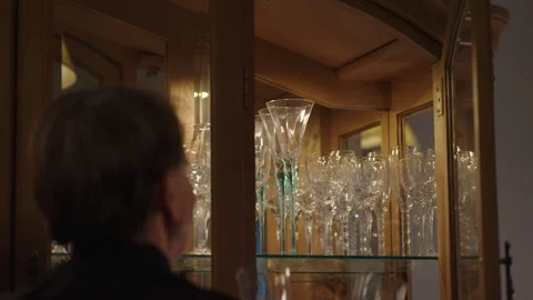 Man taking two wine glasses out of china hutc Video stock 284901657
