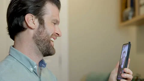Man taking video call on his cell phone working from home on desktop computer Stock Footage 152889329