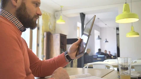 Man taking video call on internet app, by tablet, in cafe, close profile shot Vídeo Stock 73292432
