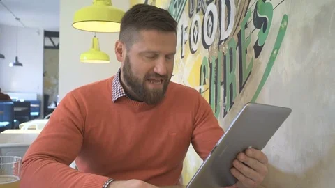 Man taking video call, skype, by tablet computer, portrait, in cafe, steadicam Vídeos de archivo 73230411