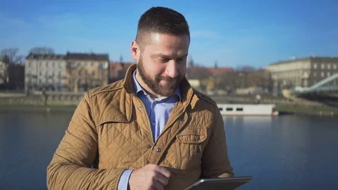 Man taking video call by tablet app, on the background of the river, portrait 動画素材 72710036