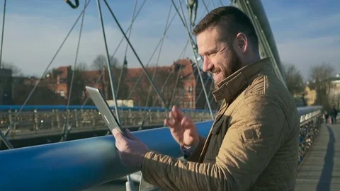 Man taking video call by tablet computer app on the footbridge, outdoor, sunset 库存影片 72711274