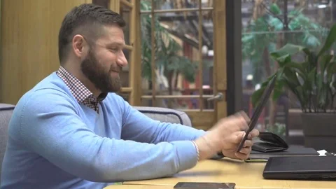 Man taking video call, by tablet computer, in cafe, profile steadicam shot Vídeo Stock 73075932
