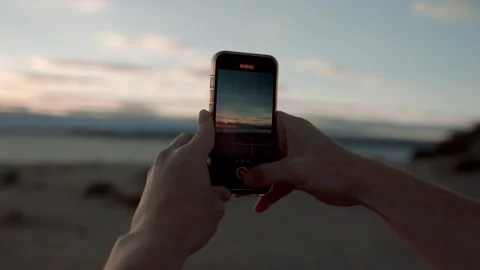Man taking video of a sunset over the beach Stock Footage 200827182