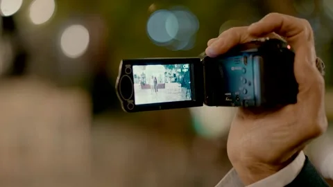 A man taking video with video camera and looks on the screen of the camera Stock Footage 225903722