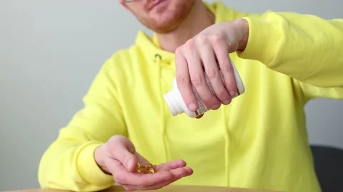 Man taking vitamins out of pill bottle. Closeup. Healthcare and medicine. Video stock 171113232