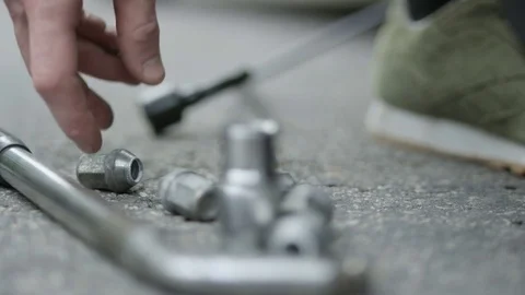 Man Taking a Wheel Nut and Putting it Back on the Ground Stock Footage 79796422