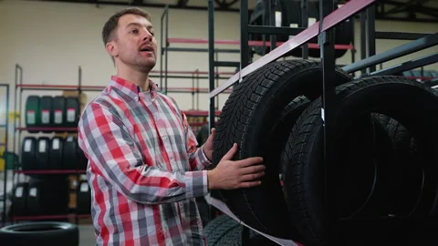 Man taking a winter tire from shelf and calling a seller Stock Footage 301551697
