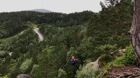 Man Taking Zip Line Ride Across The Green Forest Trees In Norway Stock Footage 130053749