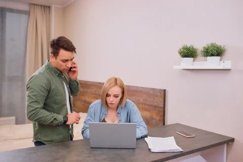 Man talk on phone while her wife sit on laptop Fotos de archivo