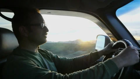 A man talking and driving at sunset on a country road Stock Footage 231691562
