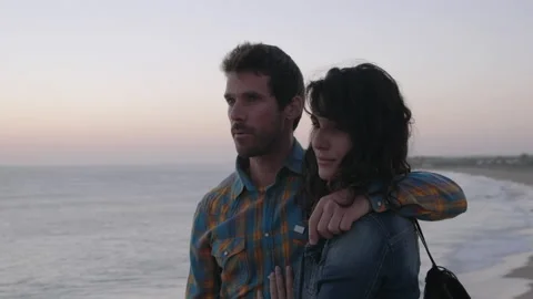 Man talking and pointing while embracing his girlfriend on beach Stock Footage 131156588