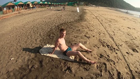 Man talking and smiling on a beach on a sunny day Vídeos de archivo 129754575