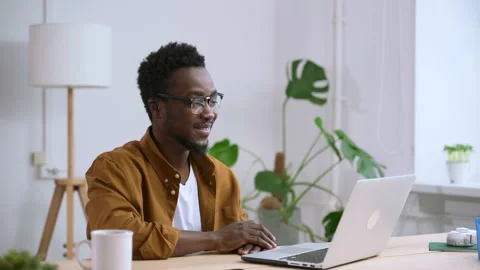 Man talking and waving hand in front of laptop screen at table in apartment Stock Footage 147650701