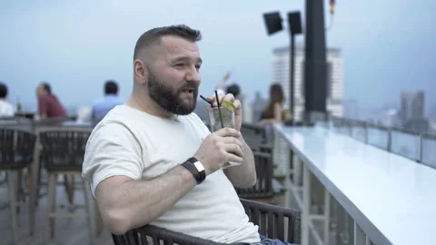 Man talking to the camera and making toast while sitting on the terrace Video stock 87545817