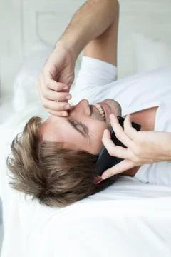Man talking on cell phone on bed Stock Photos