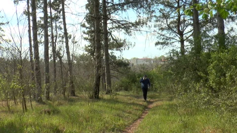 A man talking on a cell phone climbs a forest path Vídeos de archivo 130577281