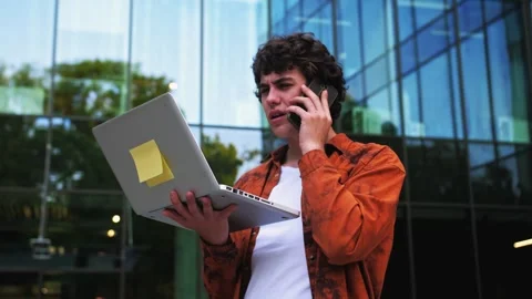 Man talking on cell phone pacing back and forth outdoors near office with Stock Footage 243375344