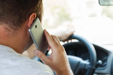Man talking on a cell phone while driving a car Stock Photos