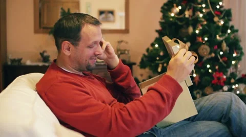 Man talking on cellphone and looking at christmas gift HD Stock Footage 10608278