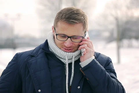 Man talking on cellphone and smiling to the camera in the park at winter time Stock-Footage 46981036