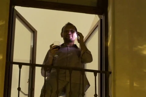 Man talking on cellphone on the balcony in the evening NTSC Stock Footage 45291955