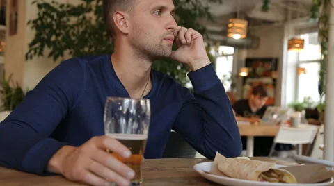 Man talking on cellphone, drinking beer in cafe Stock Footage 67861888