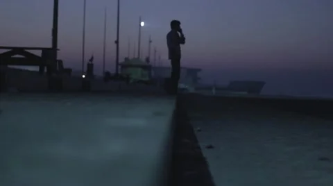 Man is talking on cellphone before sunrise at the beach Stock Footage