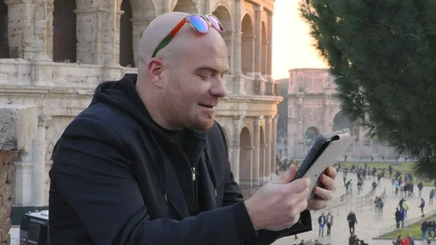 Man talking with a friend by digital tablet- Colosseum in background Video stock 92780204