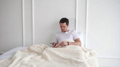 Man is talking with a friend lying in bed. Stock Footage 81909325