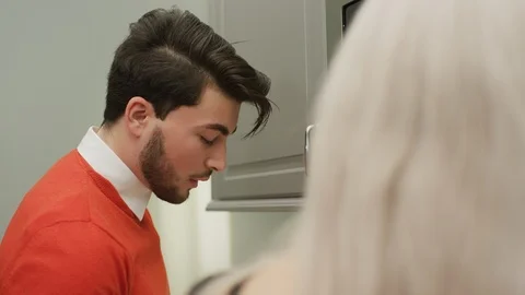 Man talking as he works in the kitchen Stock Footage 99940488