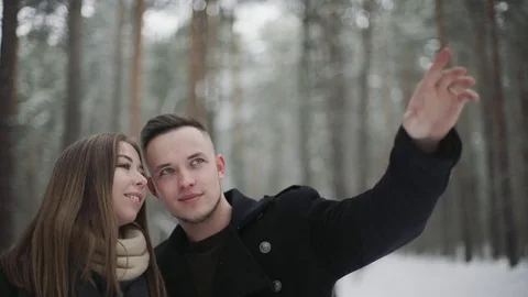 Man talking with his girlfriend in the winter forest and shows something around Stock Footage 73035122