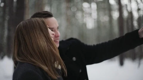 Man talking with his girlfriend in the winter forest and shows something around Stock Footage 73035774
