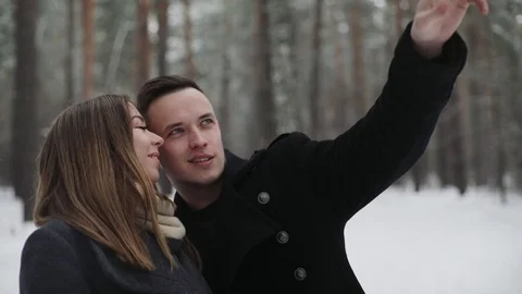 Man talking with his girlfriend in the winter forest and shows something around Stock Footage 73035939