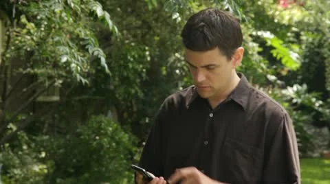 Man Talking on his iPhone in the Park Stock Footage 11237804