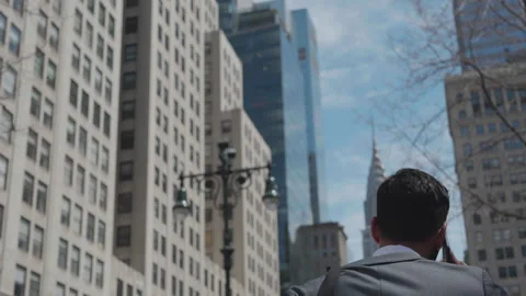 Man talking on his phone while walking through city streets in daylight Stock Footage 312685550