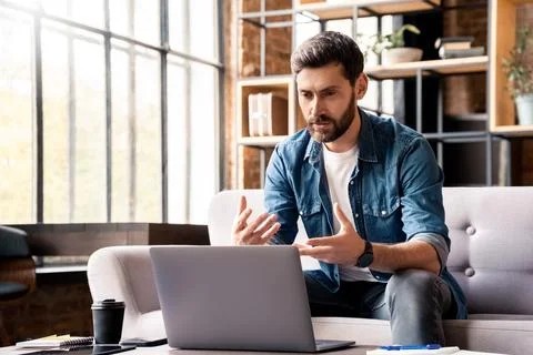 Man talking looking at laptop screen holding videoconference at home office Stock Photos