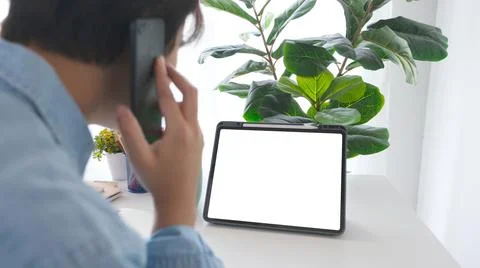 Man talking mobile phine while looking at digital tablet with blak screen on Stock Photos