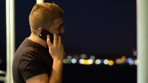 A man talking on a mobile phone against the backdrop of the night city. 動画素材 101401513