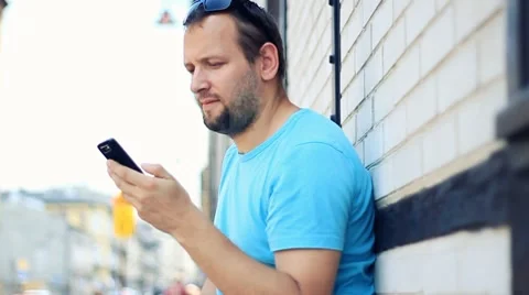 Man talking on mobile phone, brick wall background Stockbeeldmateriaal 7766079