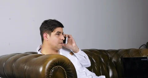 Man Talking on Mobile Phone on Leather Sofa Stock Footage 120432884